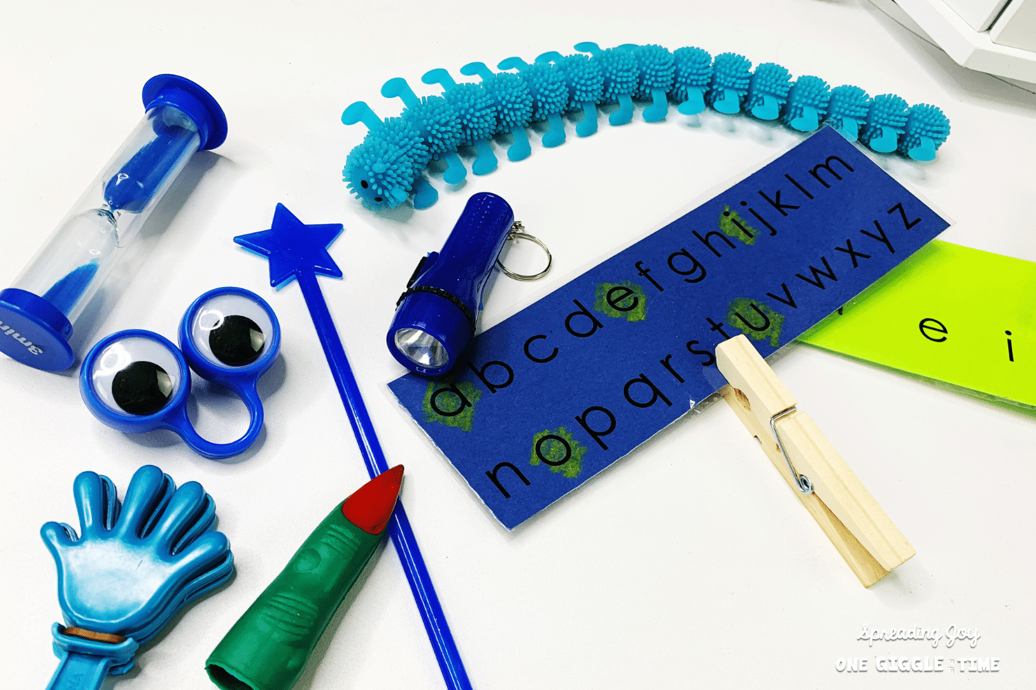 fun learning tools for kids: timer, squishy stretchy caterpillar, google eyed finger puppet, star topped swizzle stick, small clapper toy, witch finger pointer, alphabet and vowel strip with clothespin.png